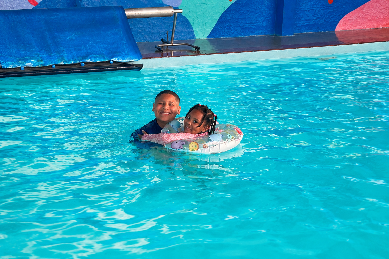 Two children smiling in the heated indoor pool on a float ring